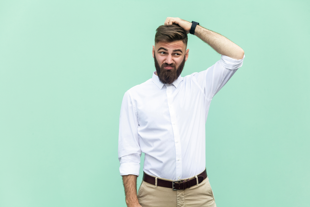 Confused businessman scratching head while evaluating vendor options, representing buyer difficulty differentiating between competitors