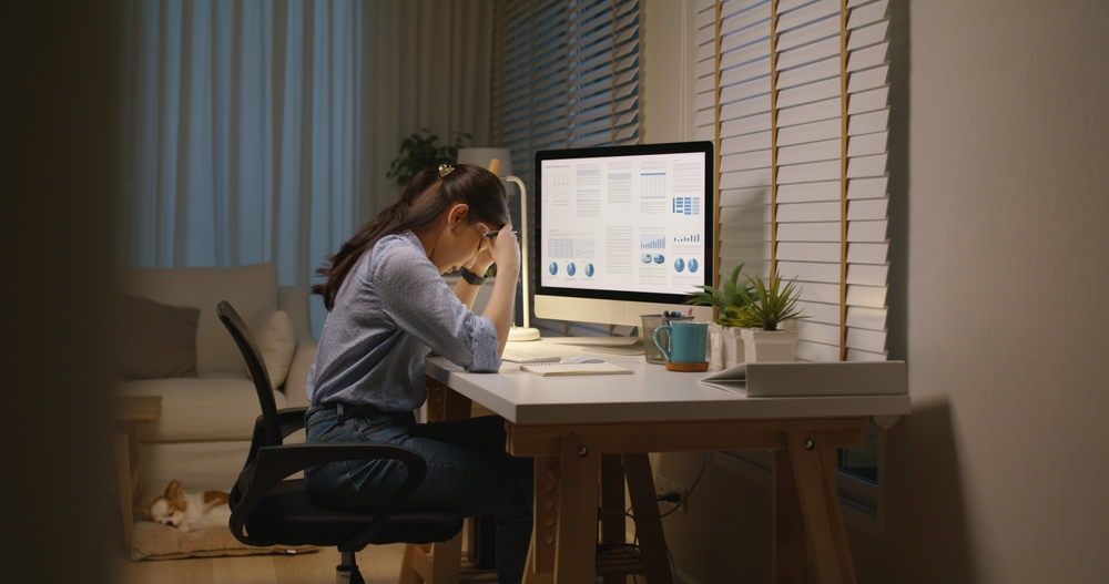 Tired marketing professional at computer reviewing outdated brand documents on screen
